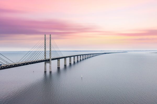 Øresundsbroen, forbindelse mellem Danmark og Sverige, himmel er lyserød og lysegul og vandet og broen fremstå grå. flot og roligt billede.