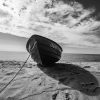 Træbåd der ligger på stranden, billedet er taget nedefra, og er i grå nuancer