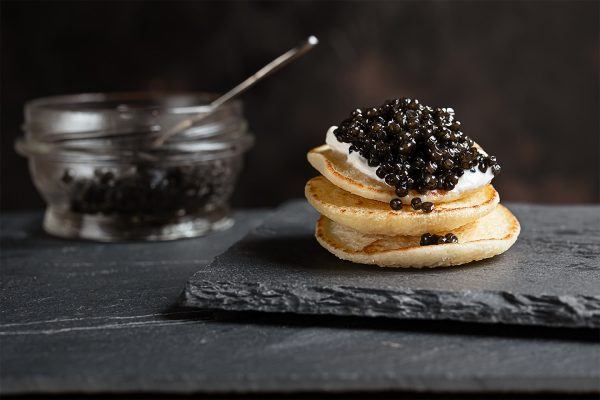 Sorte kaviar på creme frais smurt blinis, anrettet på sort skifer plade